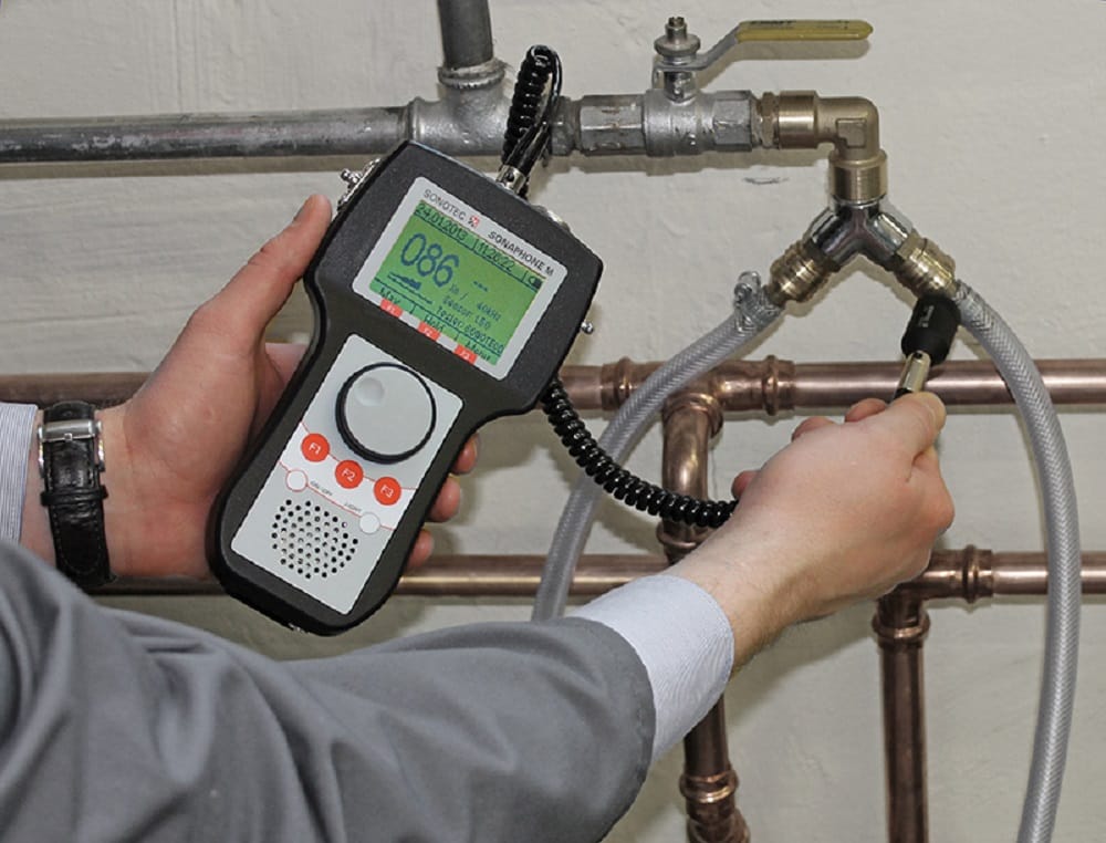 Plumber testing pipes with electronic leak detection equipment in Holiday