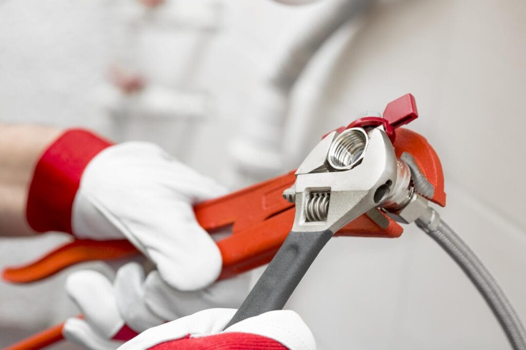 Plumber holding pipe wrenches for an emergency repair in Holiday