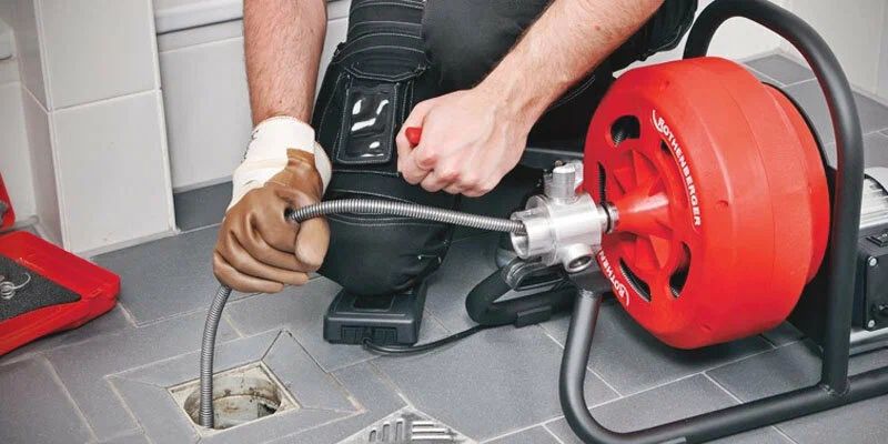 Plumber using a drain-cleaning machine in Holiday