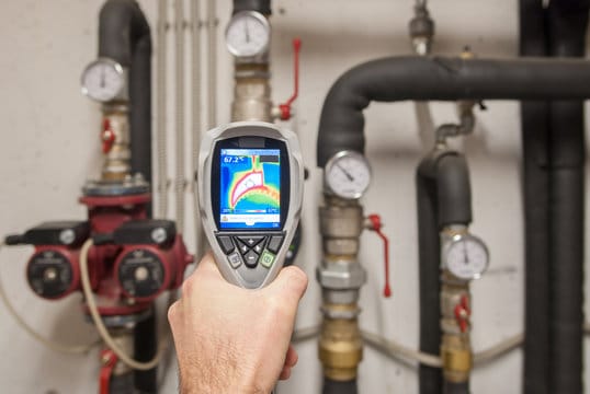 Plumber using a thermal imaging camera to inspect pipes in Holiday