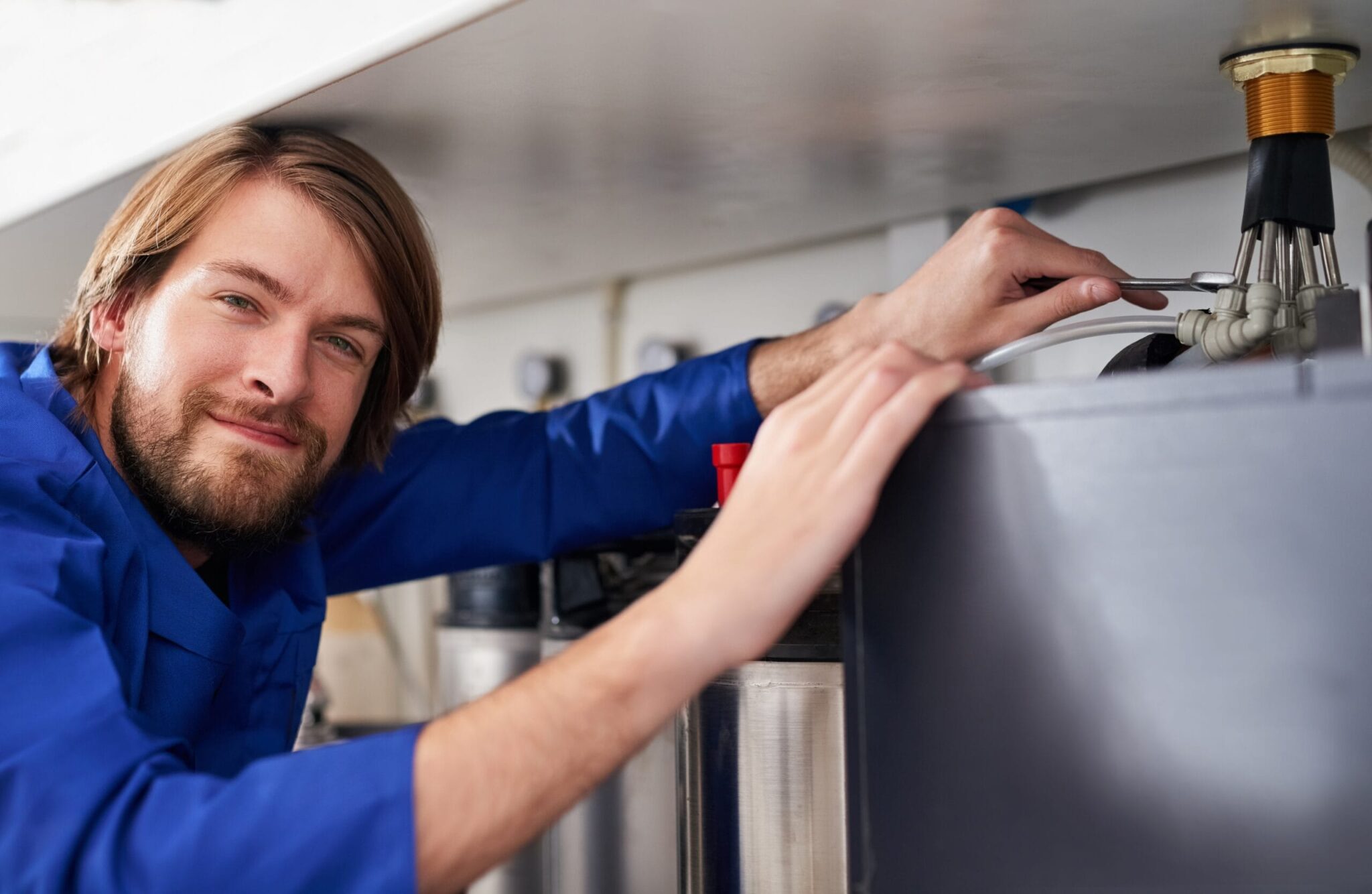 Technician servicing a residential water heater tank in Holiday